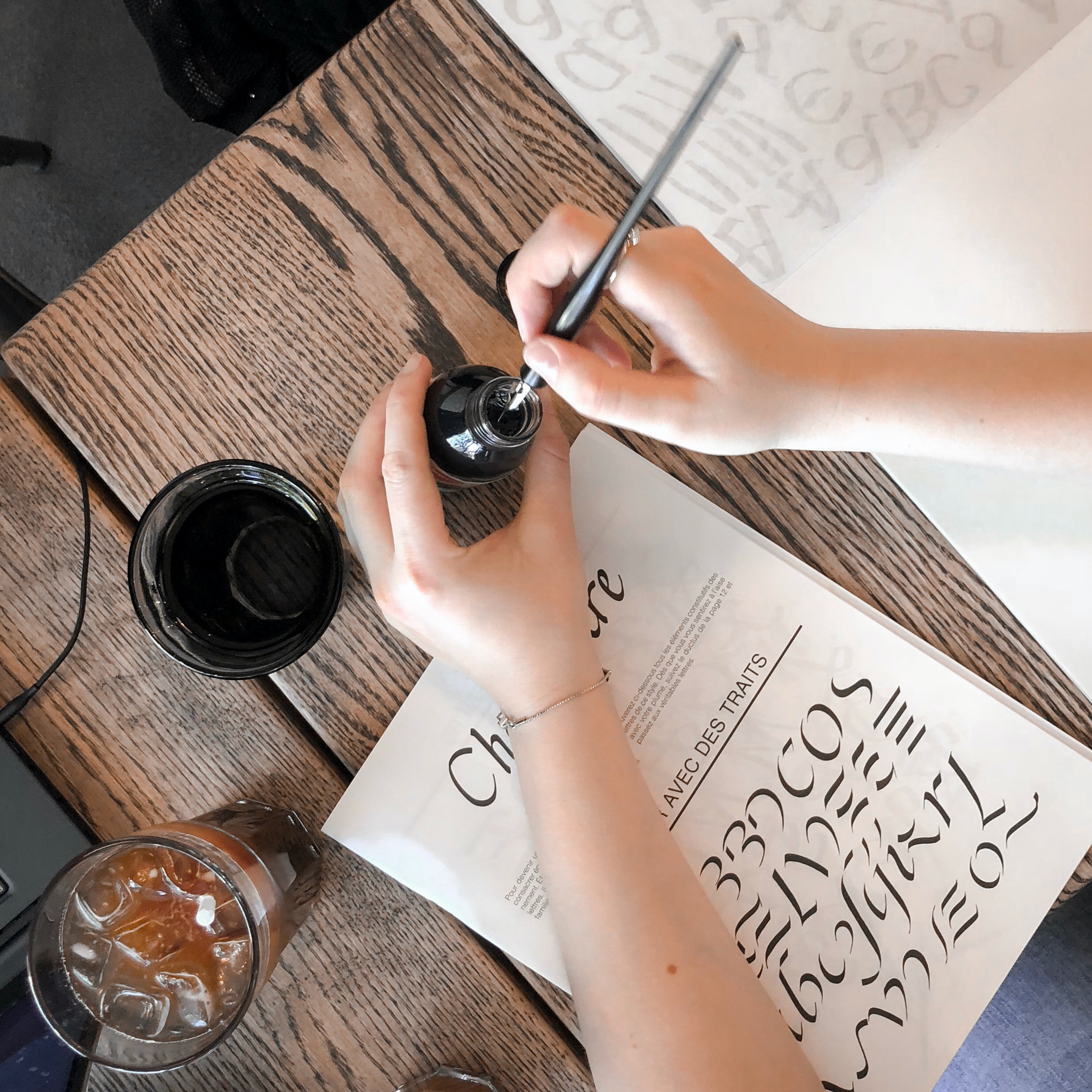 A ladie holding a old fashion pen and a ink getting ready to write into a paper